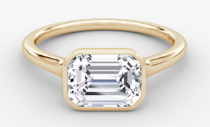 East-west emerald-cut lab-grown diamond ring in a yellow gold bezel setting